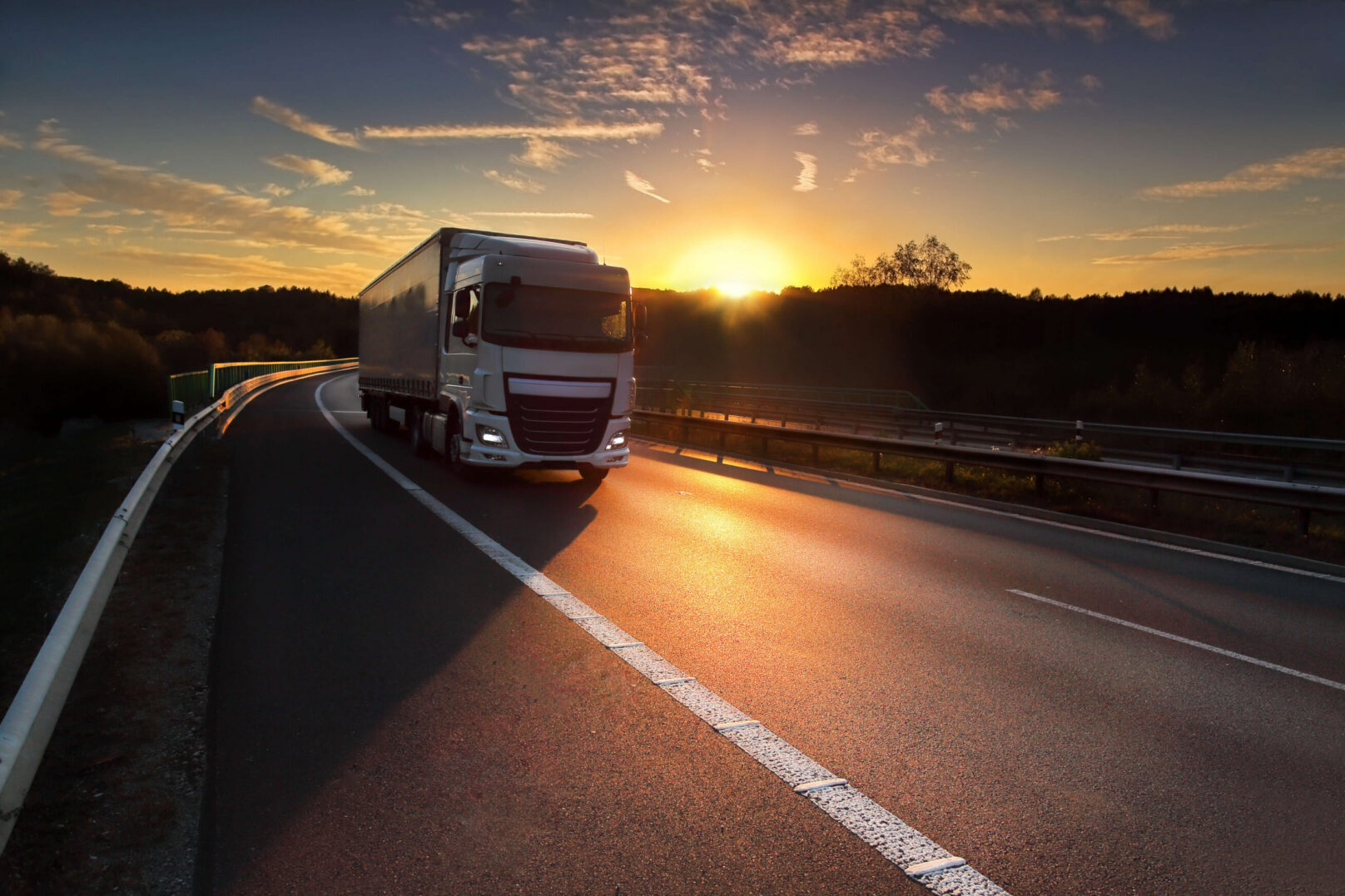 Truck rounding highway curve at golden sunset
